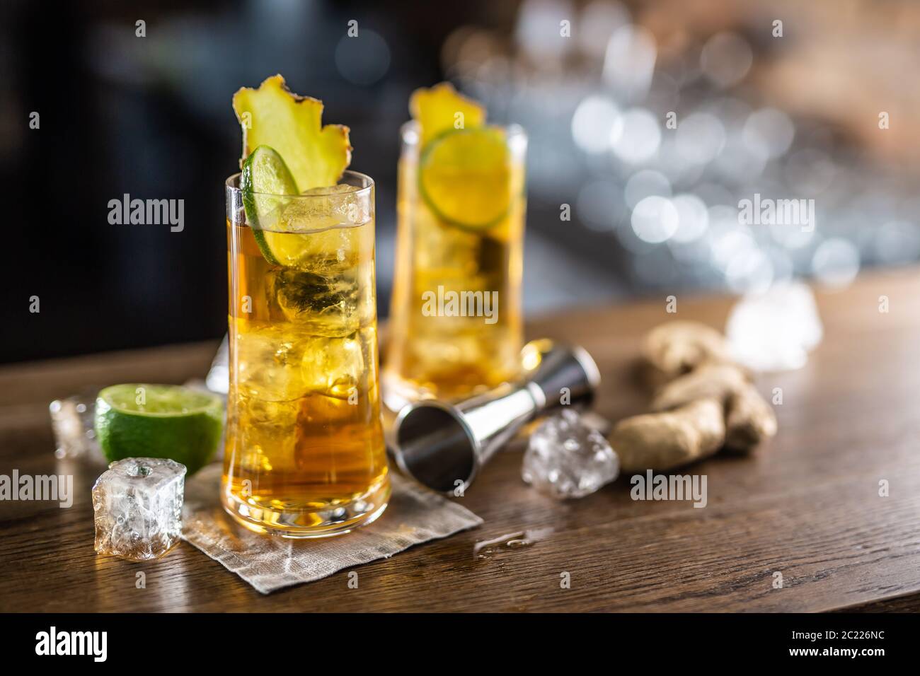 Zwei Gläser Ingwer Bourbon Cocktail mit Eiswürfeln und frischem Ingwer auf einer Holzoberfläche Stockfoto