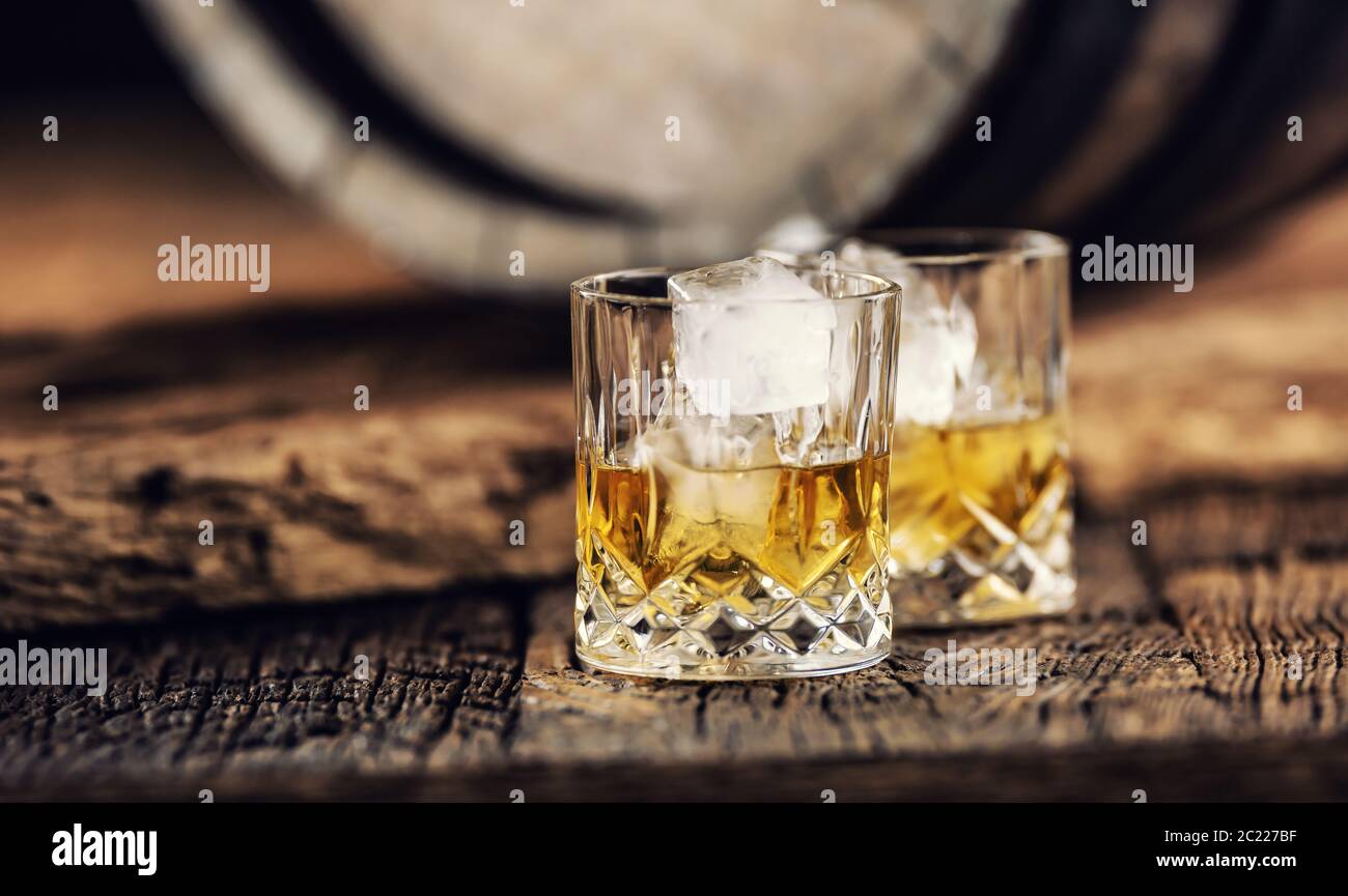 Whisky auf Eis in rustikaler dunkler Holzumgebung Stockfoto
