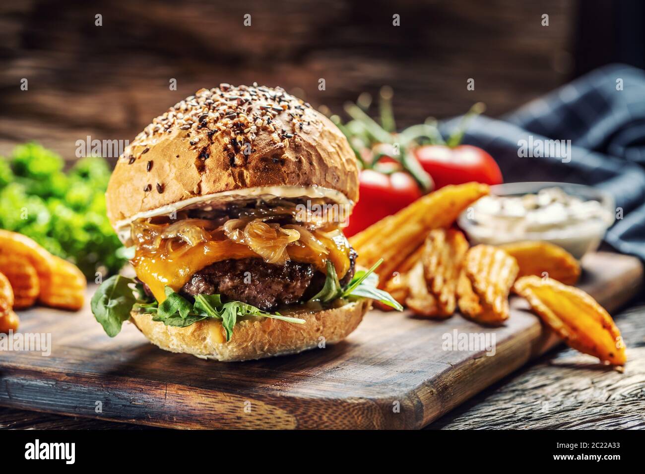 Hamburger mit karamellisierter Zwiebel, Rucola und geschmolzenem Käse Stockfoto