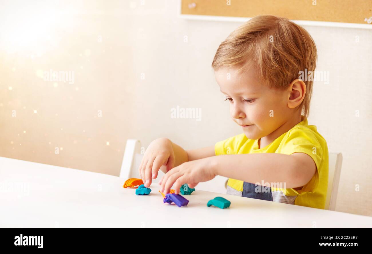 Kaukasische Baby blonde Skulpturen aus Kinderteig für die Bildhauerei zu Hause am Tisch, Kinder und Kreativität, die Entwicklung von Feinmotorik Stockfoto