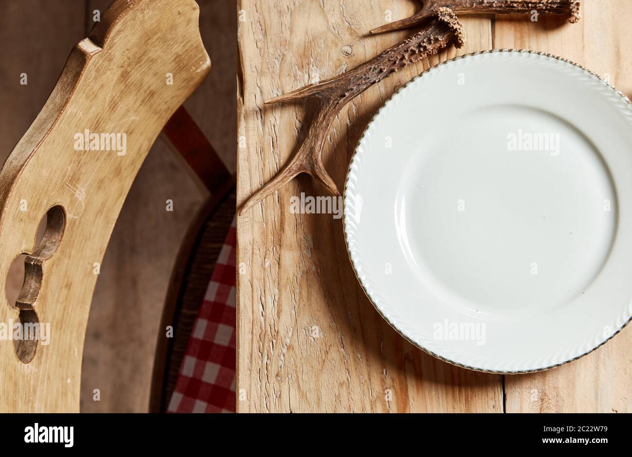 Leere weiße Platte neben einem Hirsch Geweih auf einem rustikalen Holztisch bereit für Essen in einer Ansicht von oben zu genießen. Stockfoto