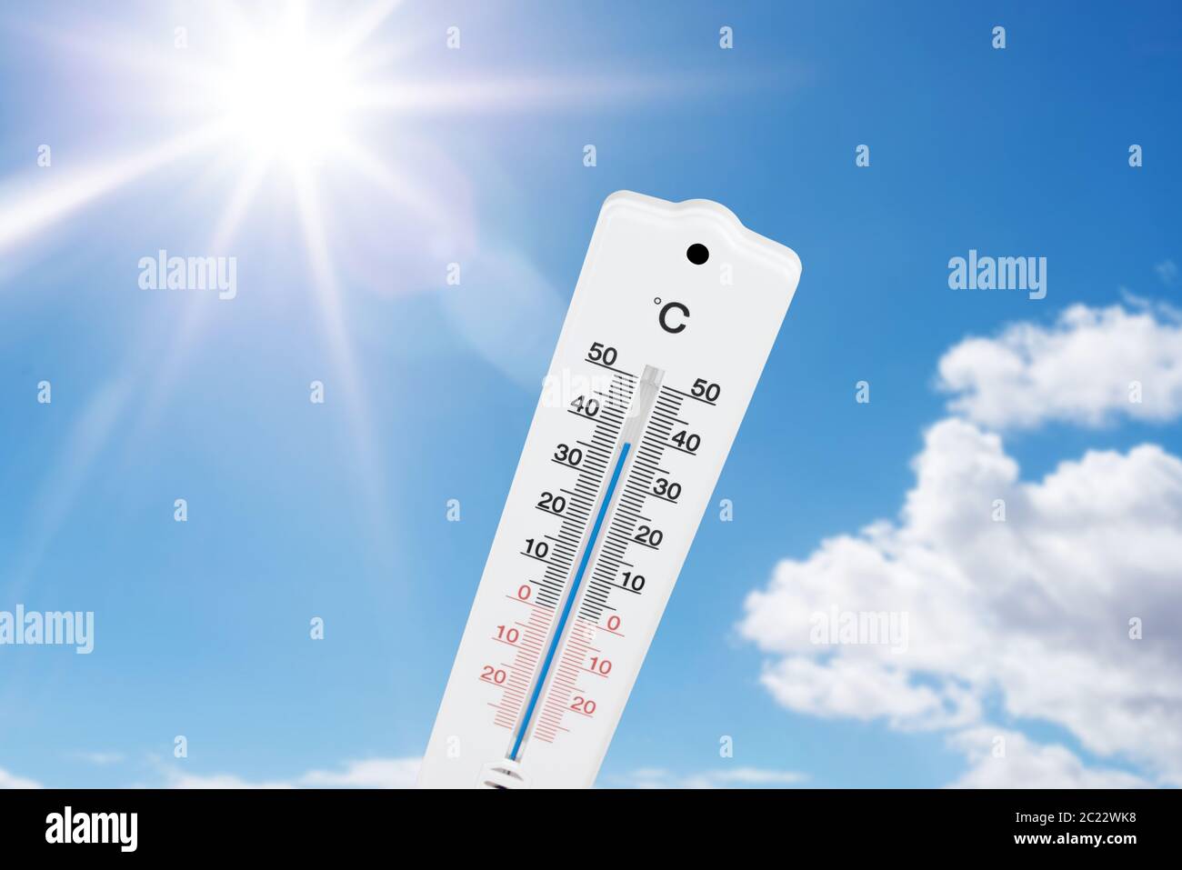 Thermometer für den Außenbereich, das hohe Temperaturen gegen blauen Sommerhimmel und Sonne anzeigt Stockfoto