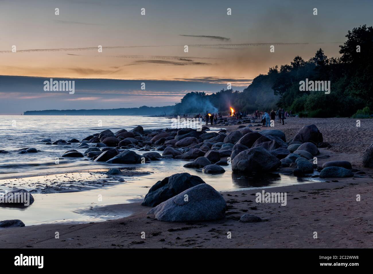 Nicht erkennbare Menschen feiern Sommersonnenwende mit Lagerfeuer am Strand Stockfoto