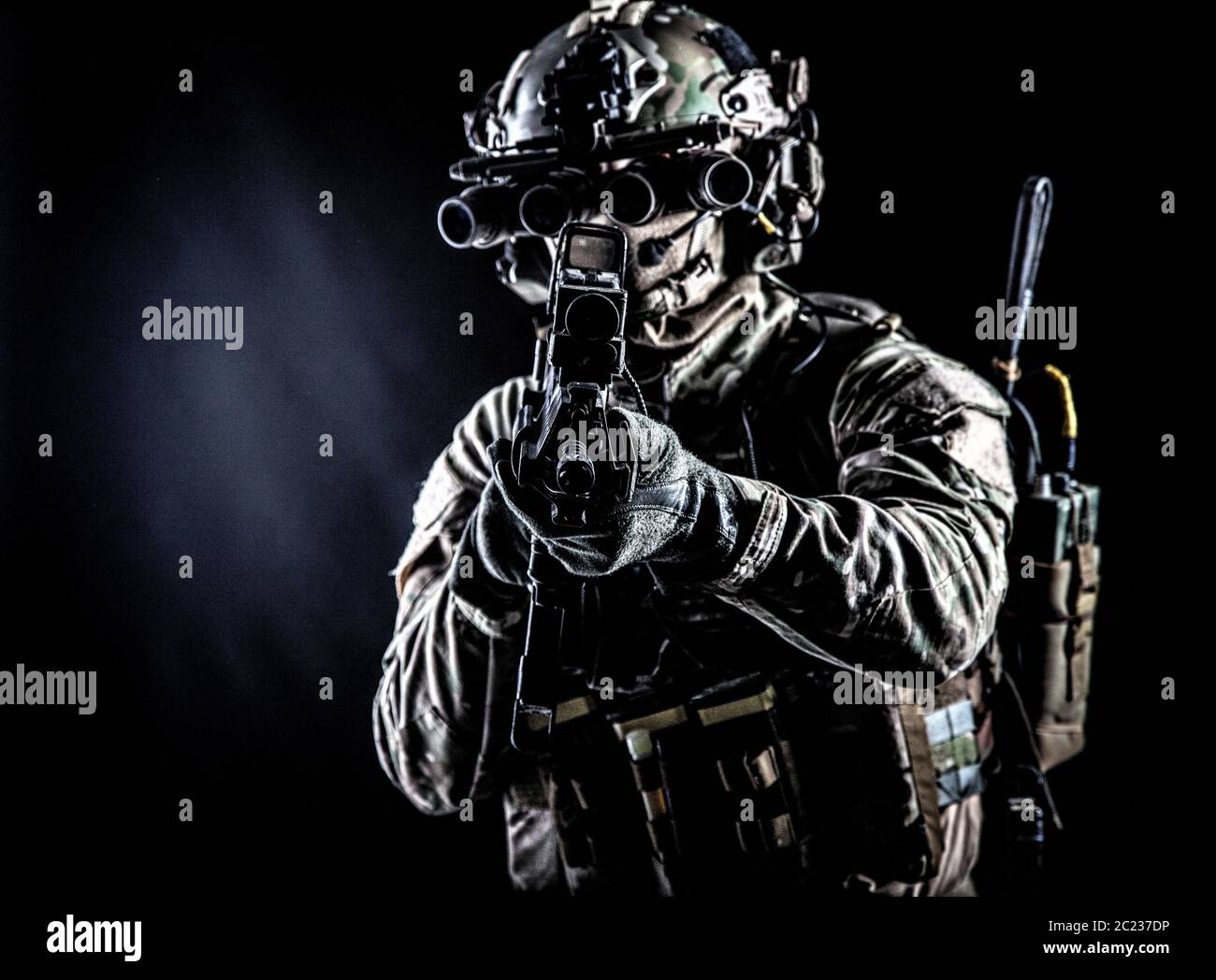 Soldat der Spezialkräfte in Camo-Kampfuniform, Lastenträger, Helm, ausgestattete Nachtsichtbrille, taktisches Funksprechset, Ziel Sturmgewehr mit Witz Stockfoto