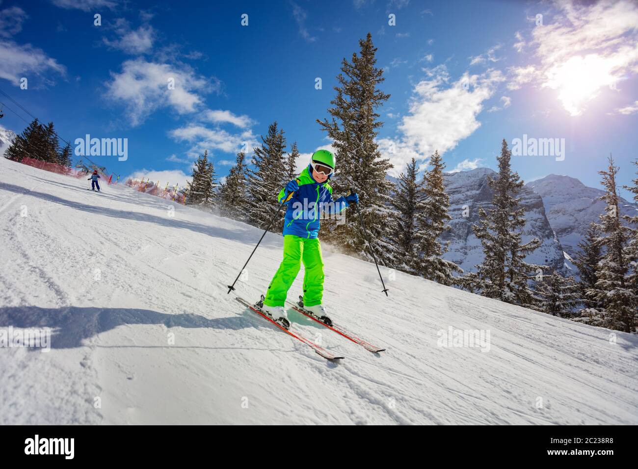 Niedliche 10 Jahre alten Jungen Skifahrer Rennen schnell abwärts in sonnigen alpinen Bergen mit Tannen auf Hintergrund Stockfoto
