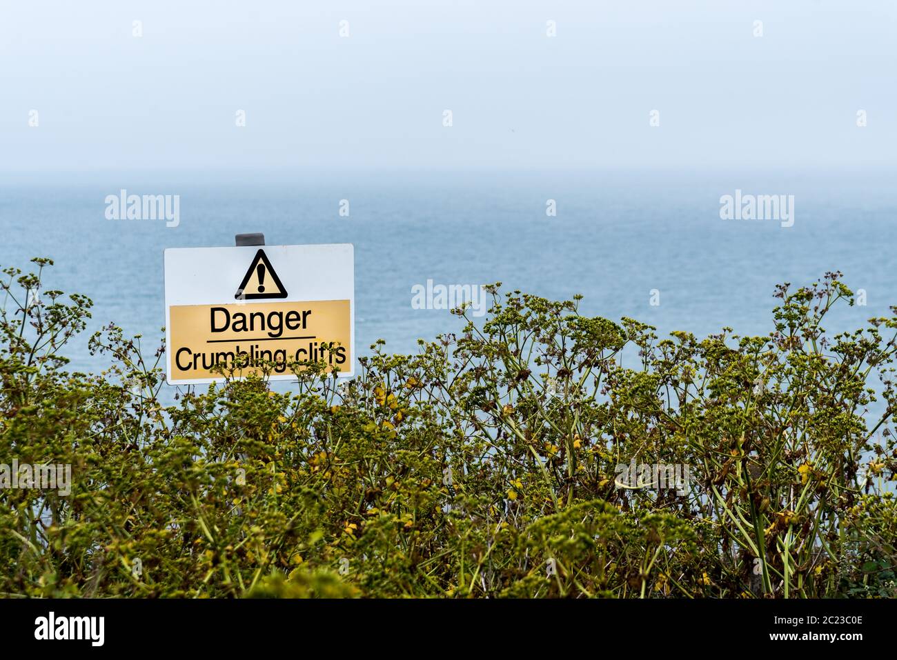 Warnzeichen der erodierenden Klippen. Beachten Sie, um zu vermeiden, in der Nähe der Klippen. Gelbes Dreieck an der Küste Warnschild. Stockfoto