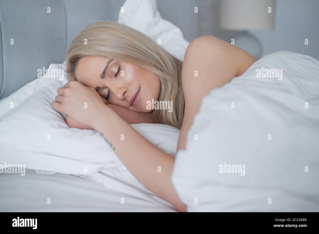 Junge hübsche blonde Frau schlafen in ihrem Schlafzimmer Stockfoto