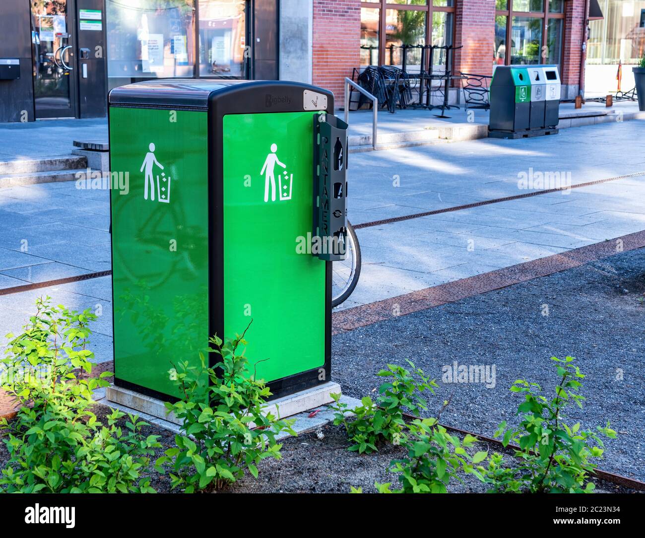 UMEA, SCHWEDEN - 10. JUNI 2020: Frisch aussehende grüne Mülltonne mit schwarzer Oberseite, einfaches Dosen-Recycling für Touristen und Einheimische, die auf der Straße spazieren, Sommerzeit, Stockfoto