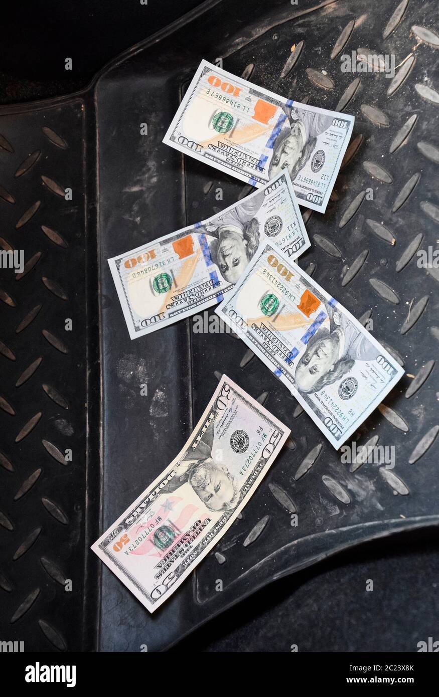 Mehrere Banknoten amerikanische Dollar liegen auf der Matte für ein Auto. Das Geld im Auto. Dollar fiel zu Boden. Stockfoto