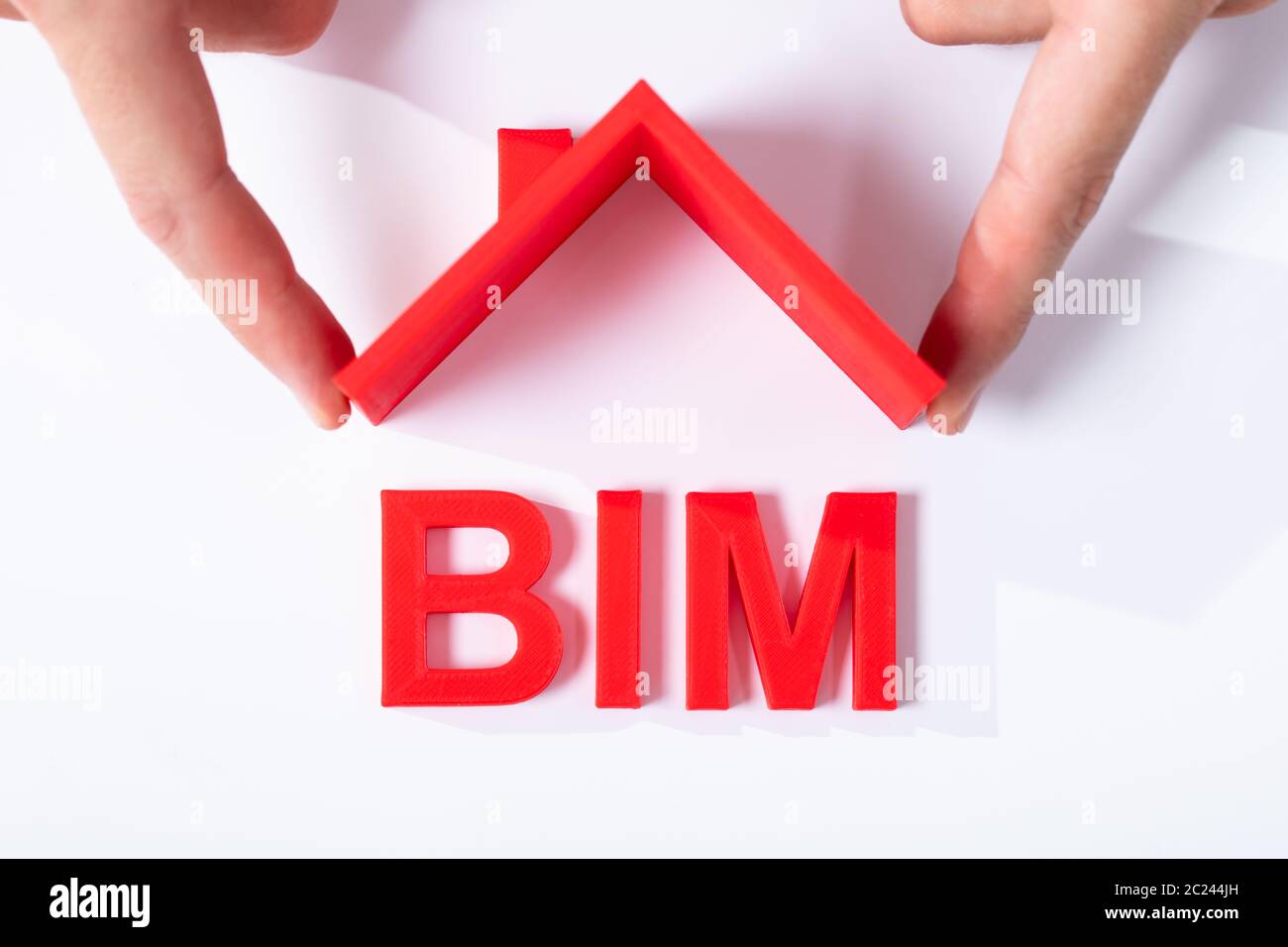Erhöhte Ansicht von der menschlichen Finger Holding Dach mit BIM Text über Weiß Schreibtisch Stockfoto