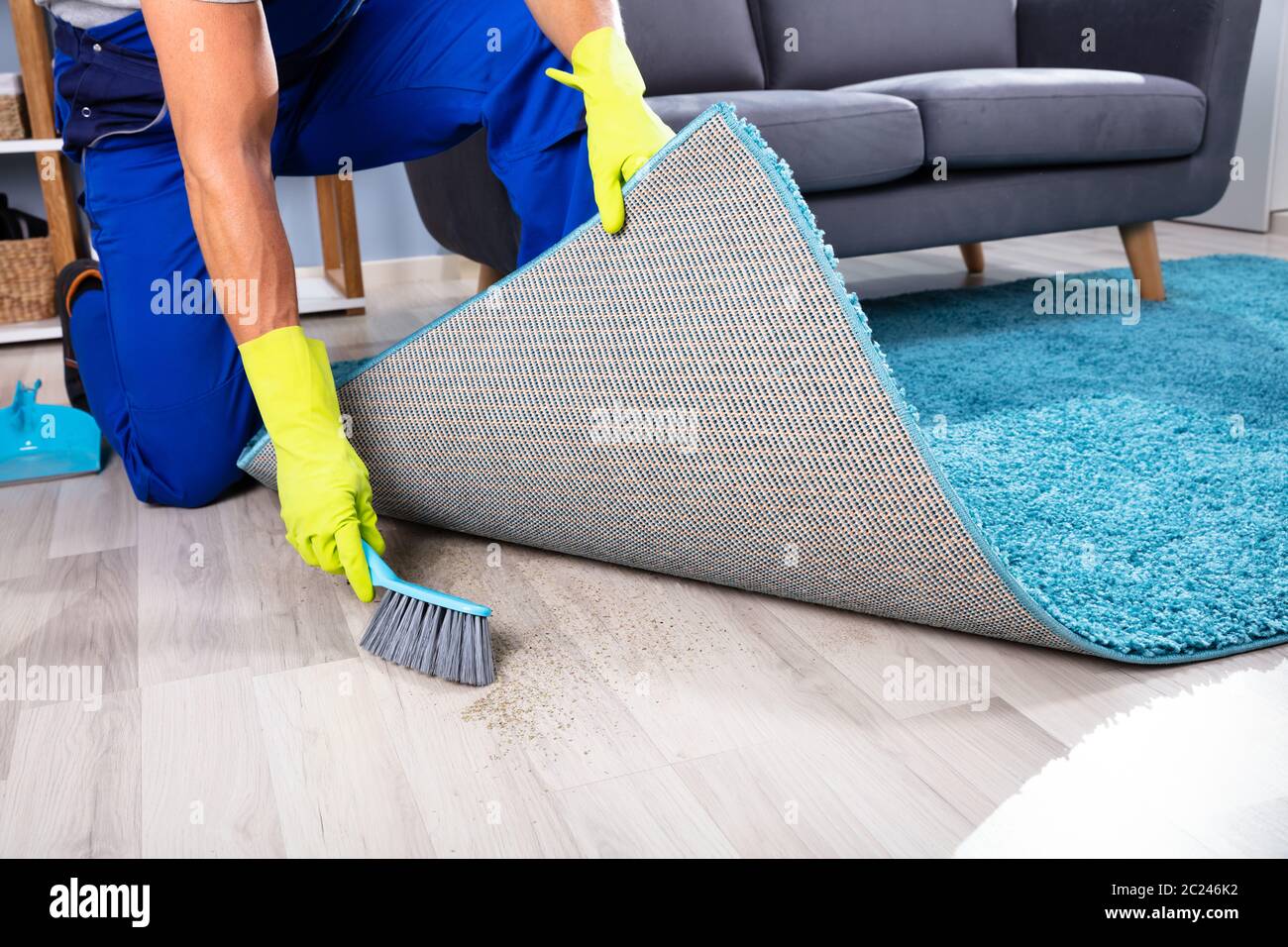 Niedrig Schnitt ein fauler Hausmeister fegt Schmutz unter den Teppich Stockfoto