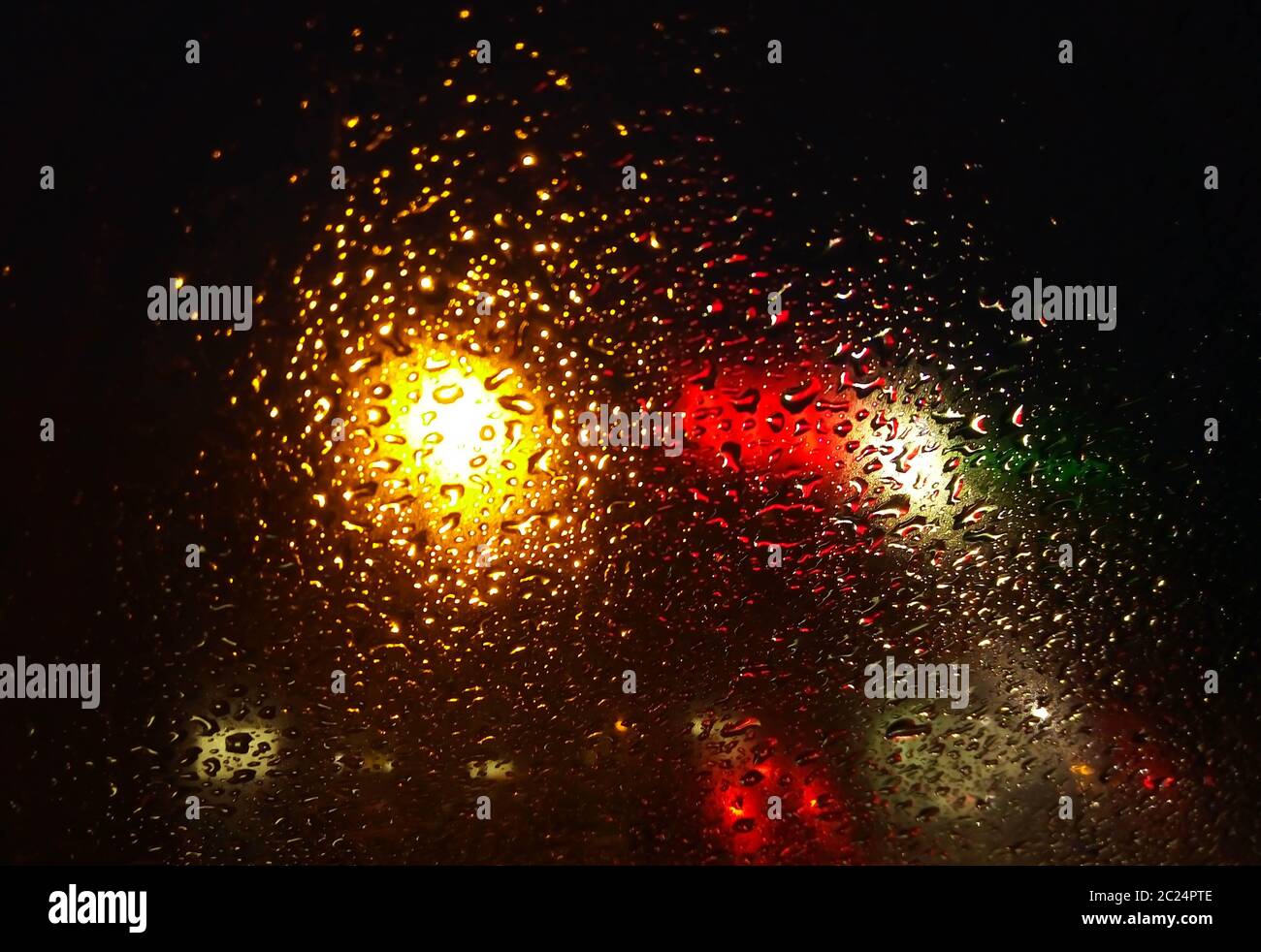 Regen fällt auf Fenster mit Straßenlicht Bokeh, Wassertropfen auf dem Glas, Nacht Sturm regnet Auto Fahrkonzept. Nachtauto. Stockfoto