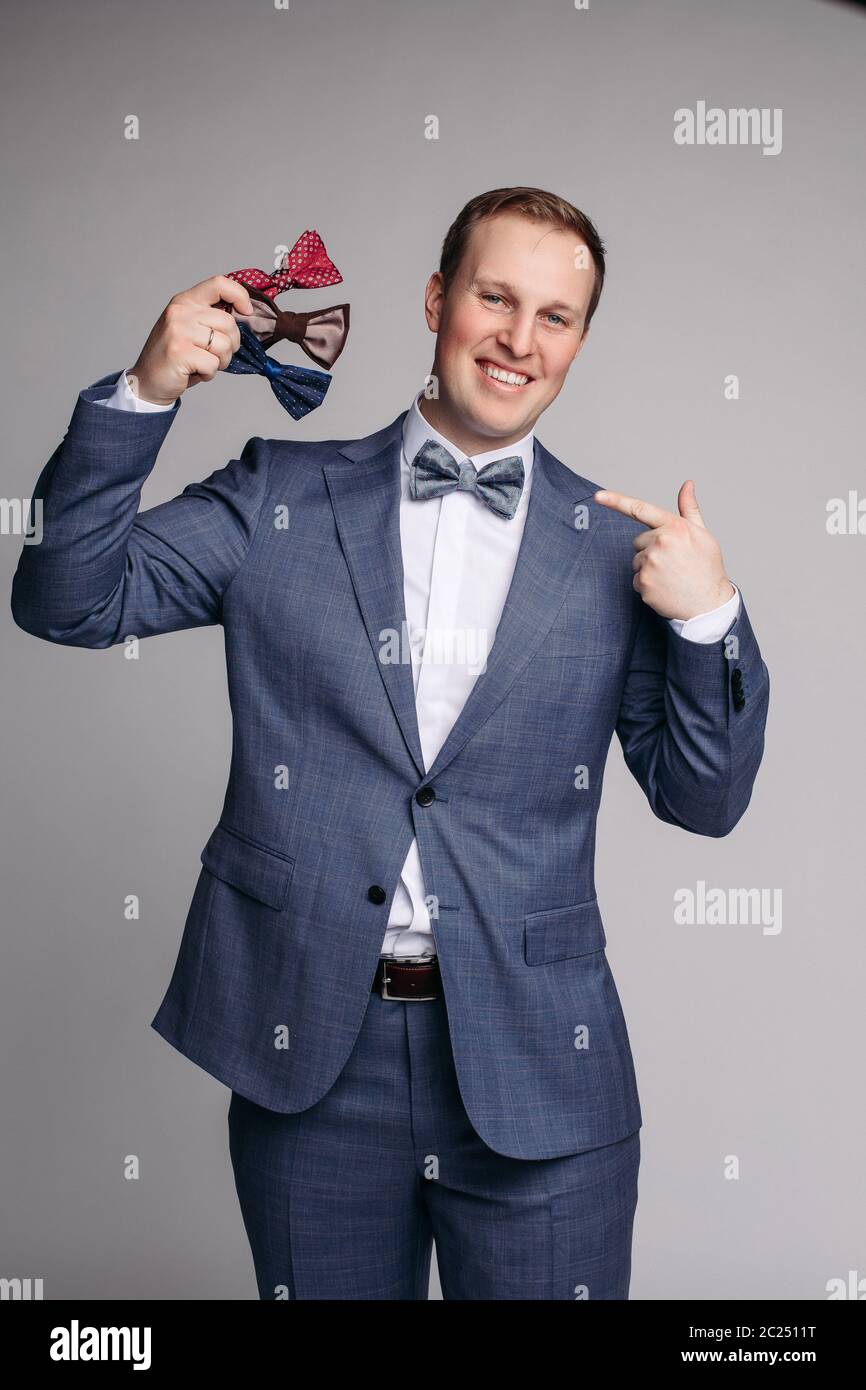 Lächelnd Mann insmart Anzug Fliege in der Hand halten. Stockfoto