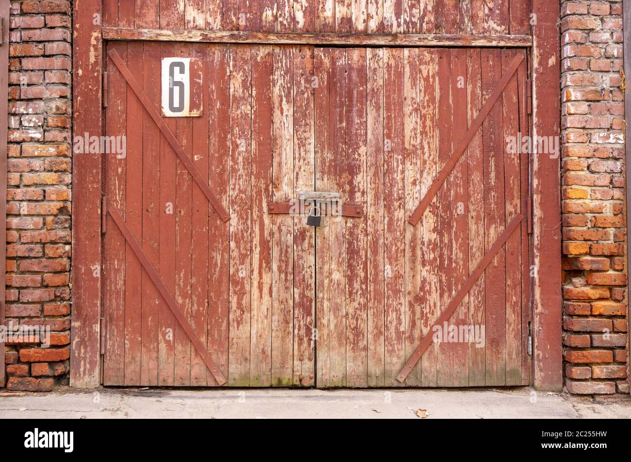 Alte Garagentür in einer weißen Betonwand. Tore aus Holz mit rissiger grüner Farbe lackiert Stockfoto