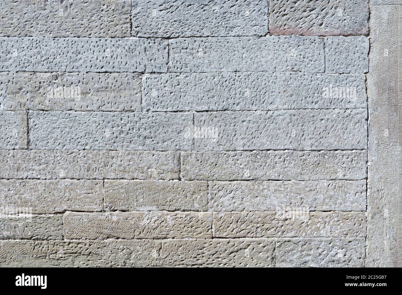 Detail einer alten grauen Steinwand aus quadratischen, länglichen Steinen mit strukturierter Oberfläche Stockfoto