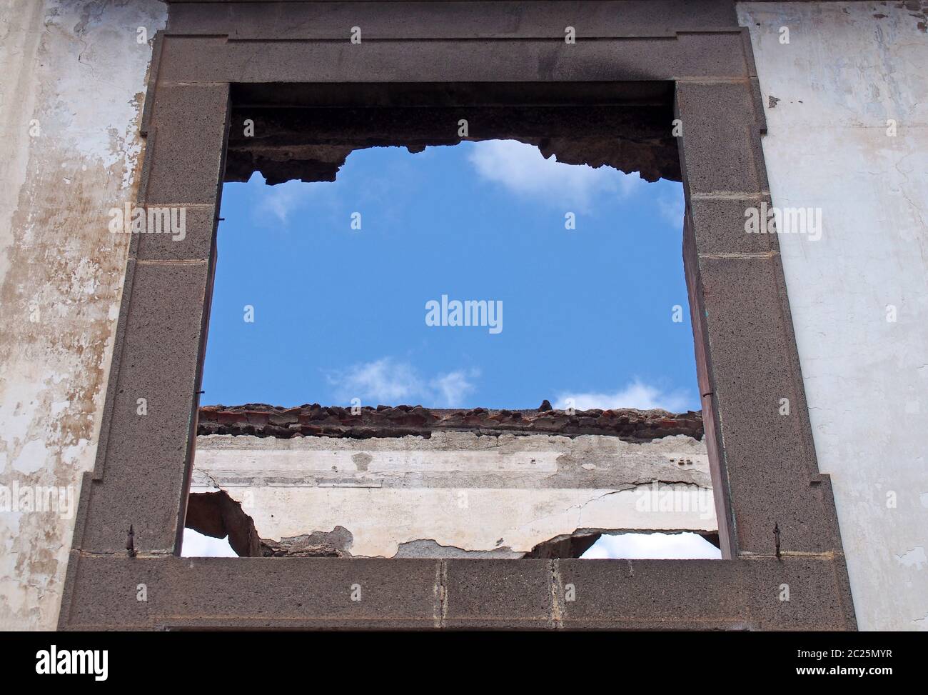 Leerer Fensterrahmen in einem überdachlosen Haus mit weißen Innenwänden vor blauem Himmel Stockfoto