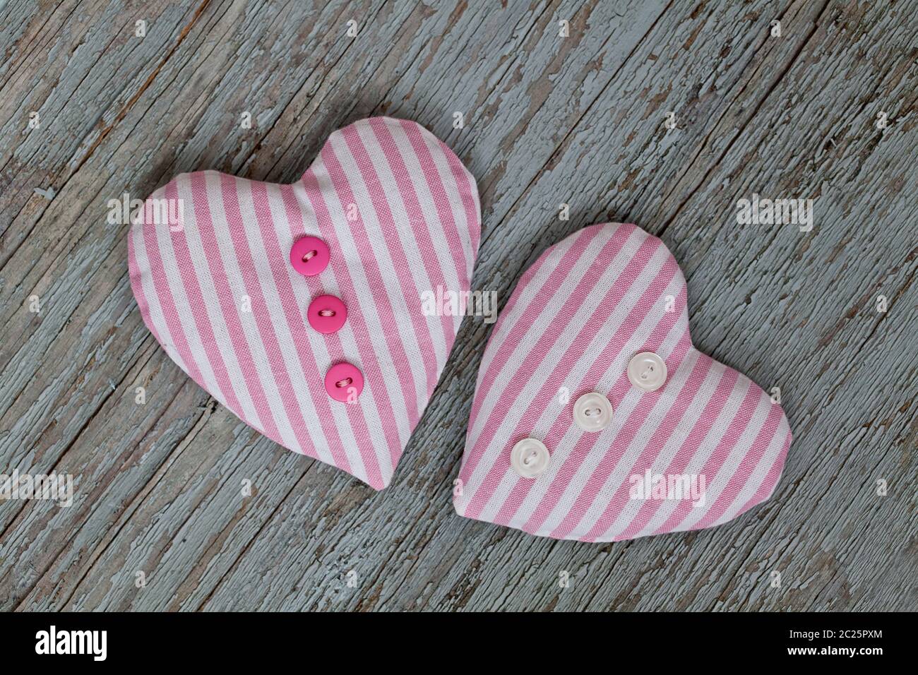 Handgefertigte Stoff Herzen aus rosa Stippstoff mit niedlichen kleinen Knöpfen, perfekt für eine Grußkarte Stockfoto