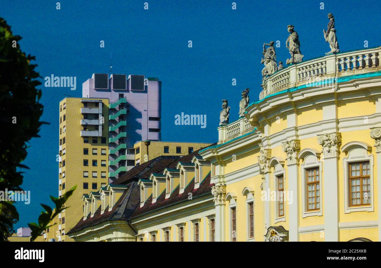 Gelbe Fassade eines Schlossgebäudes mit modernem Wolkenkratzer im Hintergrund und blauem Himmel Stockfoto