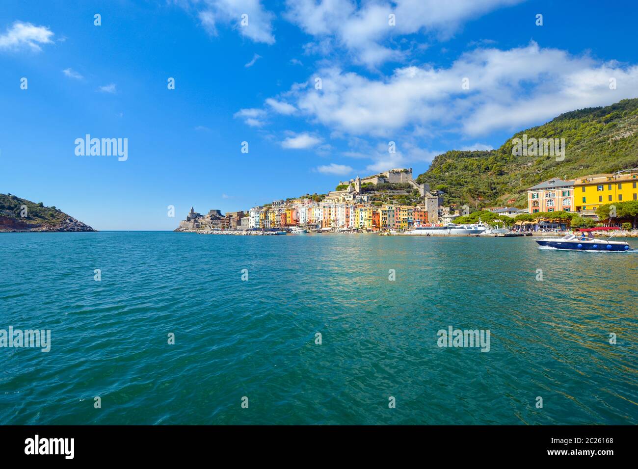 Ein Schnellboot überquert den bunten Hafen des Dorfes Portovenere, Italien, an der ligurischen Küste bei Cinque Terre. Stockfoto