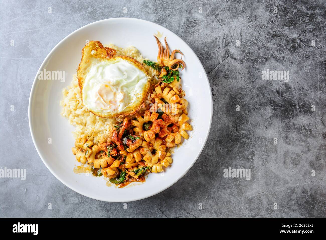 Würzig gebratener Tintenfisch mit Basilikumblättern und Chili, Sunny Side Up Ei Stockfoto