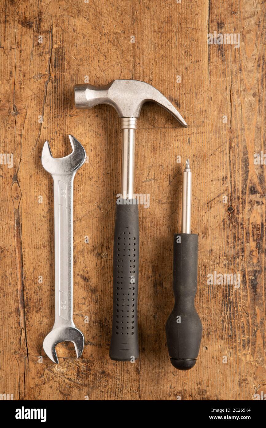 Hammer, Schneidezange, Schraubendreher und Schlüssel auf Holzhintergrund Stockfoto