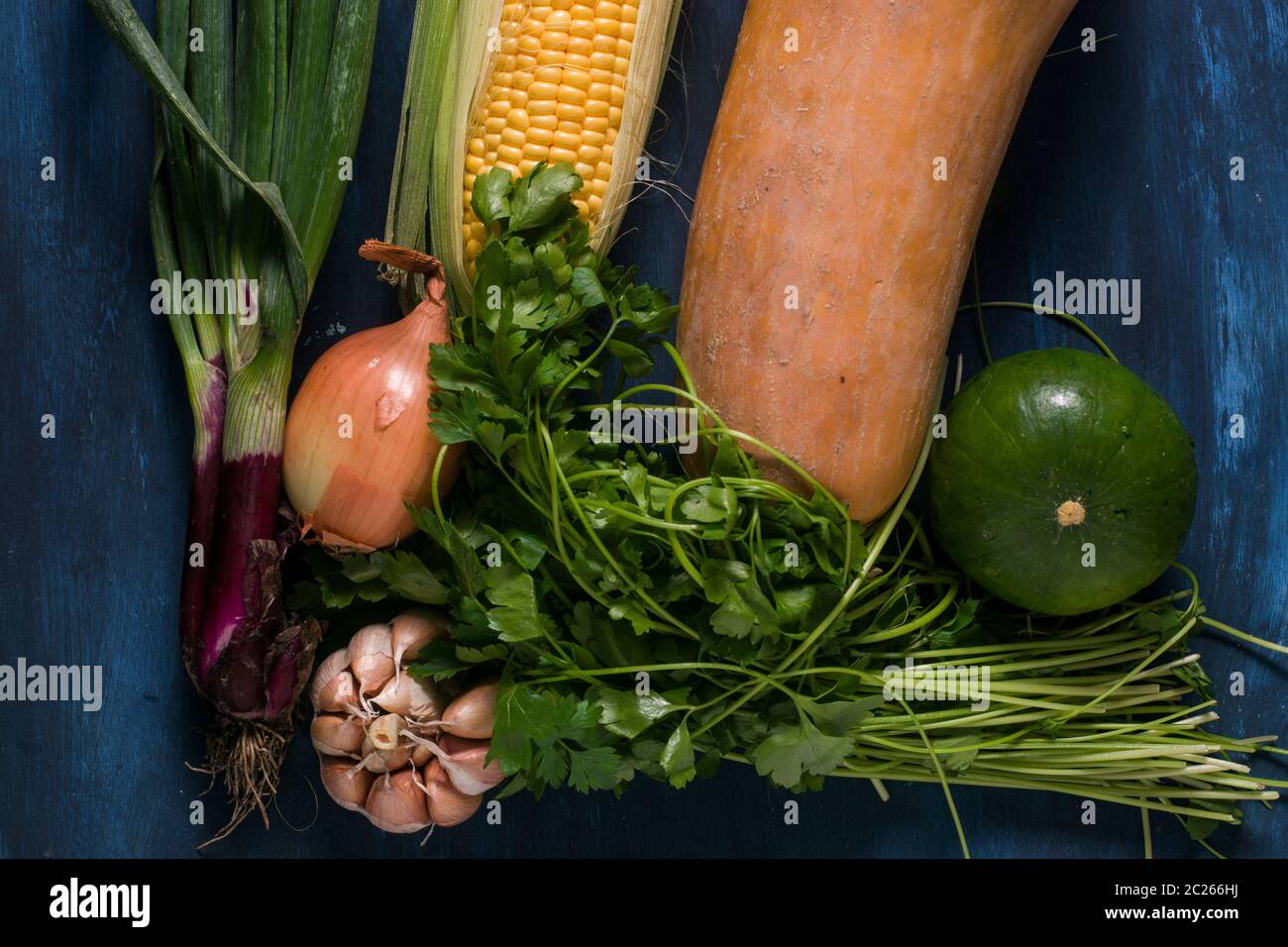 Knoblauch, Mais, Kürbis und Zwiebeln auf einem blauen Tisch Stockfoto