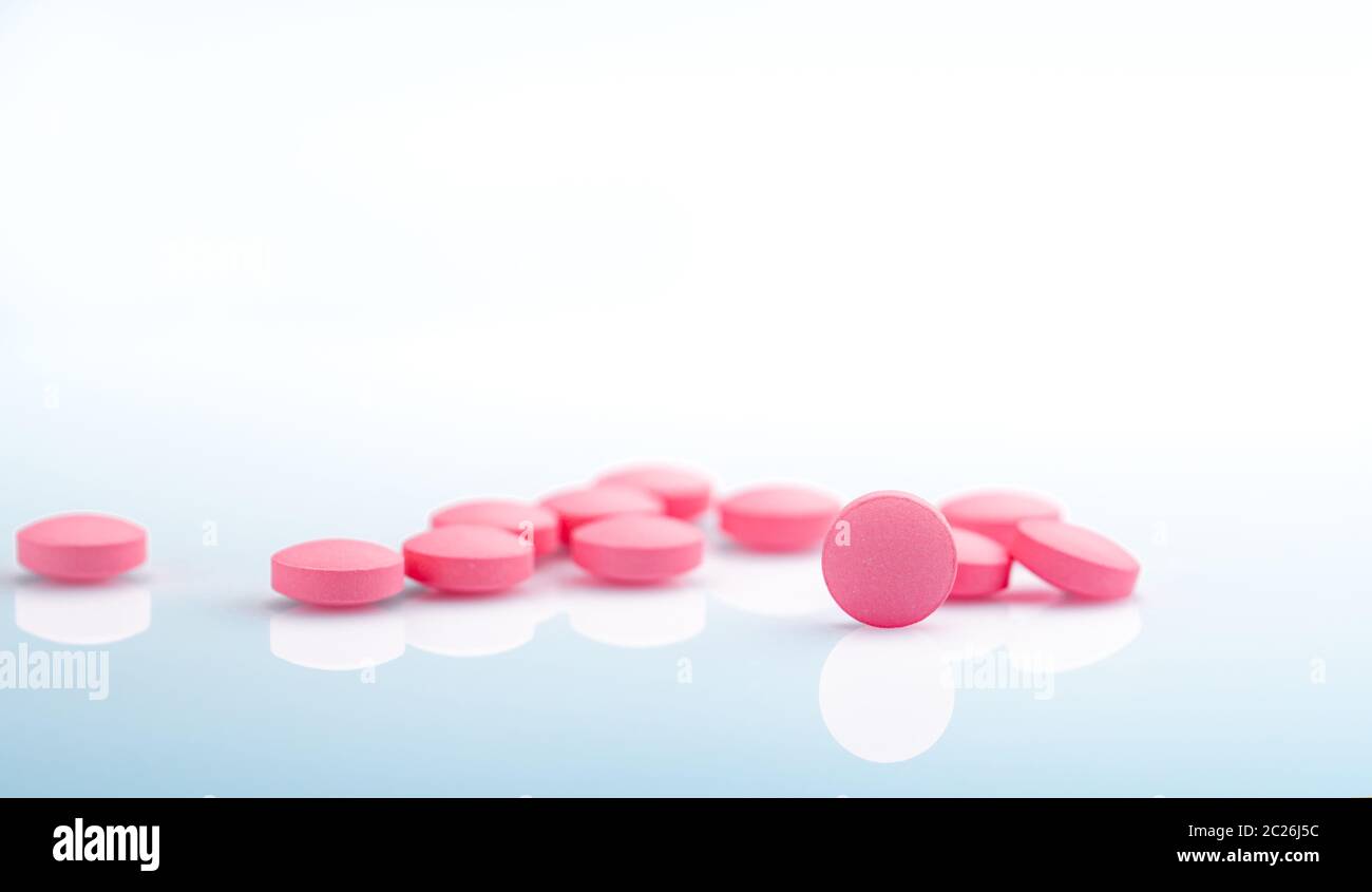 Runde rosa Tabletten Pille auf weißem Hintergrund. Vitamine und Mineralien plus Folsäure, Vitamin E und Zink in der Droge Flasche auf farbverlauf Hintergrund. Rosa Tabl Stockfoto