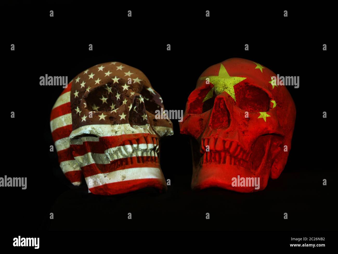 Zwei Schädel mit chinesischer und amerikanischer Nationalflagge oder Emblem, die auf der Oberfläche isoliert auf einem schlichten schwarzen Hintergrund projiziert werden. Stockfoto