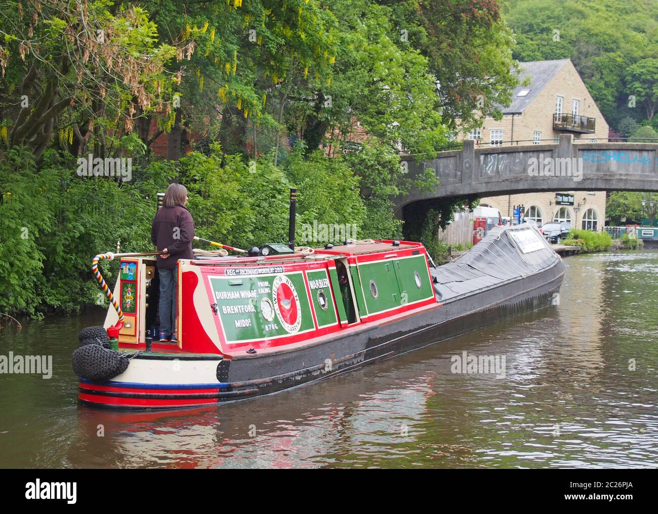 Frau, die einen alten Lastkahn steuert, der zum historischen Treffen des engen Bootclubs geht, das am Mai am rochdale-Kanal stattfindet Stockfoto