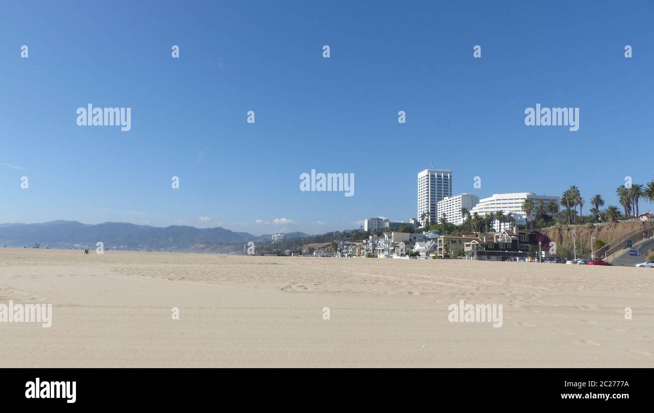 Menschenleerer, breiter Strand von Santa Monica im Großraum von Los Angeles, Kalifornien, im Hintergrund die Santa Monica Mountains, strahlend blauer Stockfoto