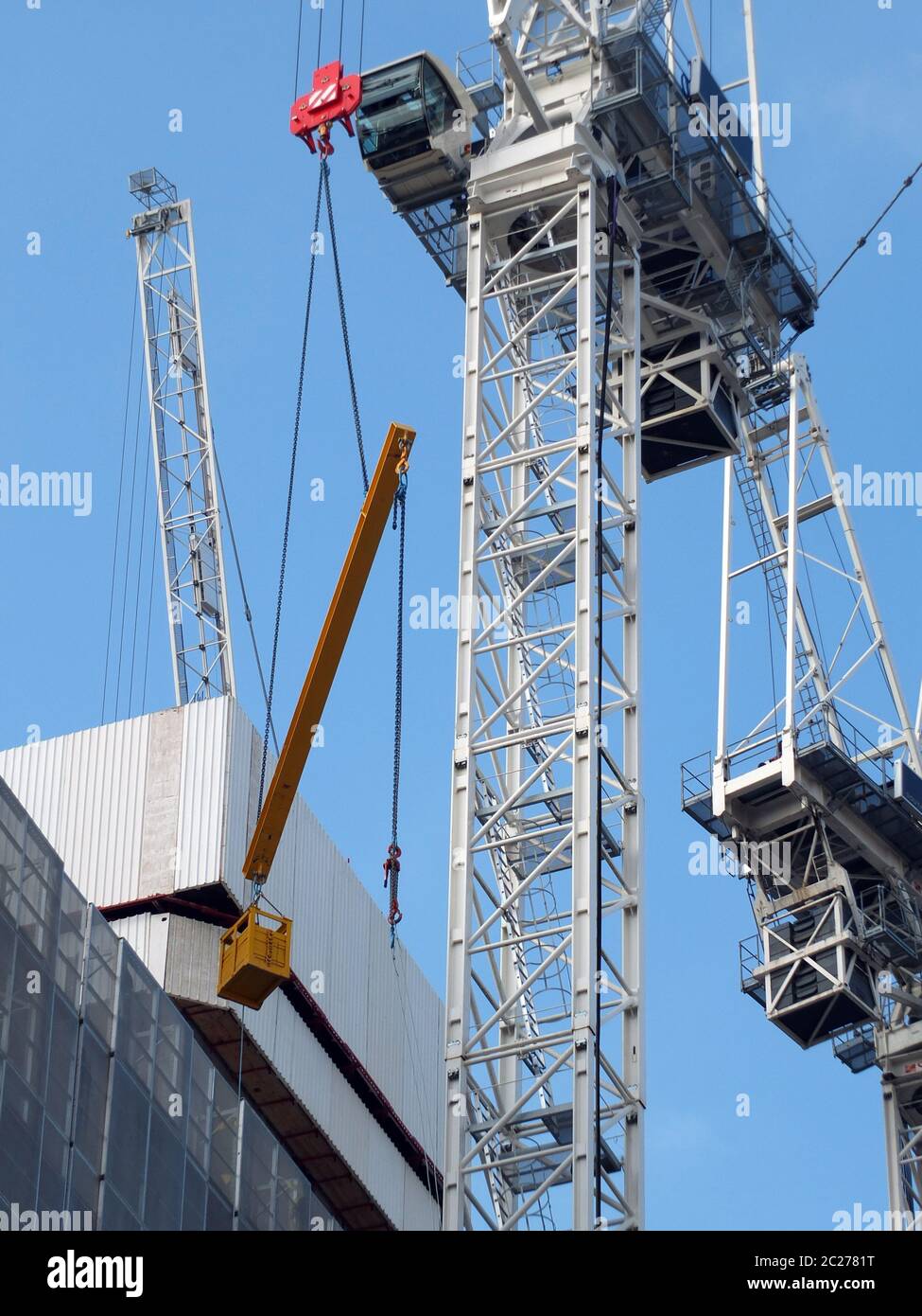 Detail eines großen Baukran, der einen großen Metallträger und Eimer hebt Stockfoto