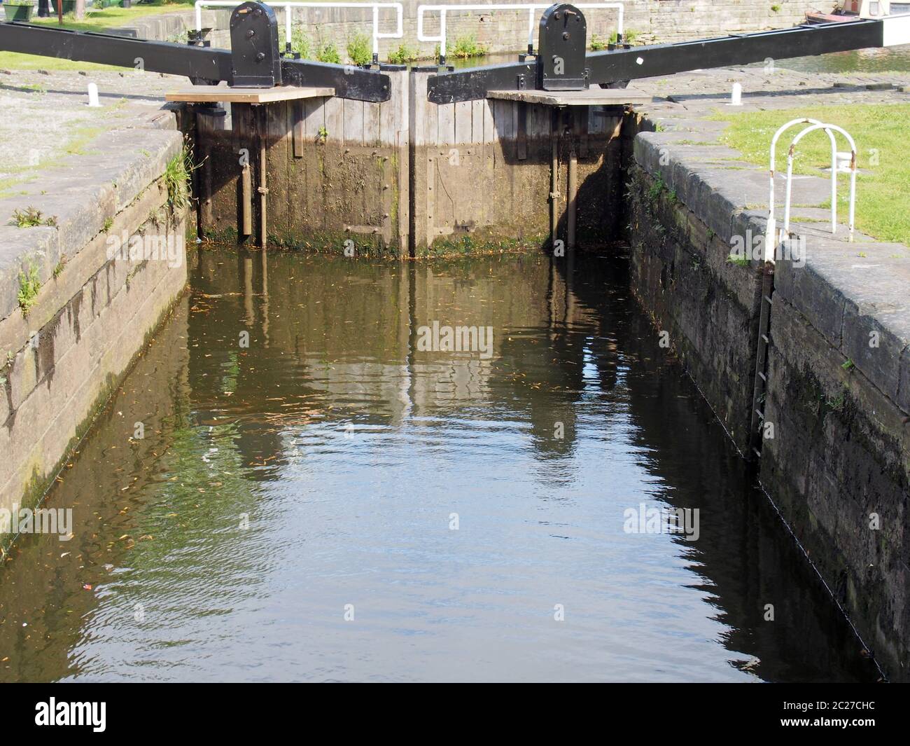 Eine Nahaufnahme von alten geschlossenen hölzernen Schleusentoren am calder- und Absteinschiffungskanal in brighouse spiegelte sich im Wasser wider Stockfoto