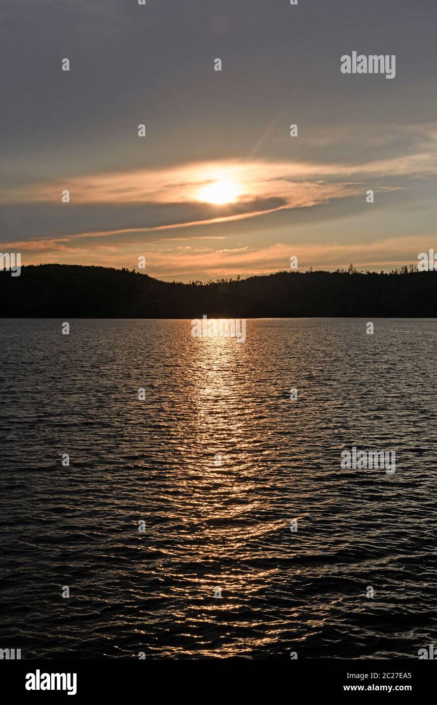Sonne lauert hinter den Wolken bei Sonnenuntergang am Knife Lake in den Boundary Waters in Minnesota Stockfoto