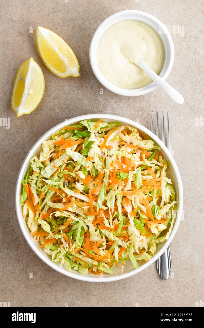 Krautsalat aus frisch geschreddertem Weißkohl und geriebener Karotte mit hausgemachtem Salat-Dressing auf Mayonnaise-Basis und Zitronenpfeilchen an der Seite, photogra Stockfoto