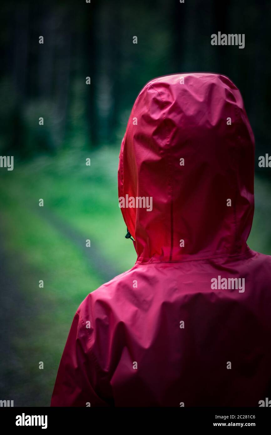 Frau mit roter Regenjacke, die auf einem Wanderweg steht Stockfoto