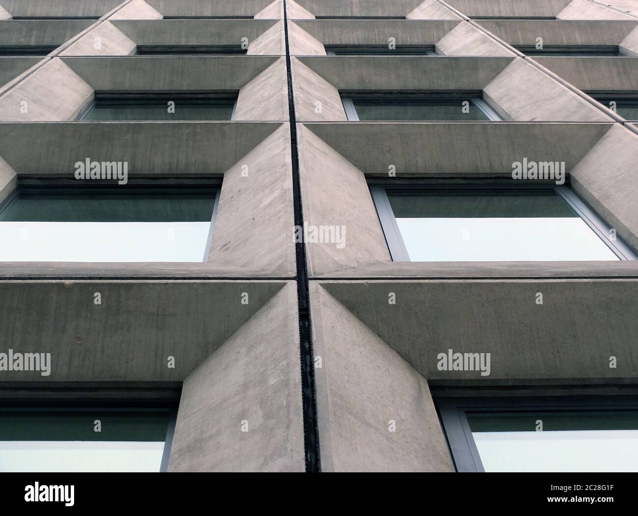 Perspektivischer Blick auf geometrische Winkelbetonfenster an der Fassade eines Gebäudes im brutalistischen Stil der 1960er Jahre Stockfoto