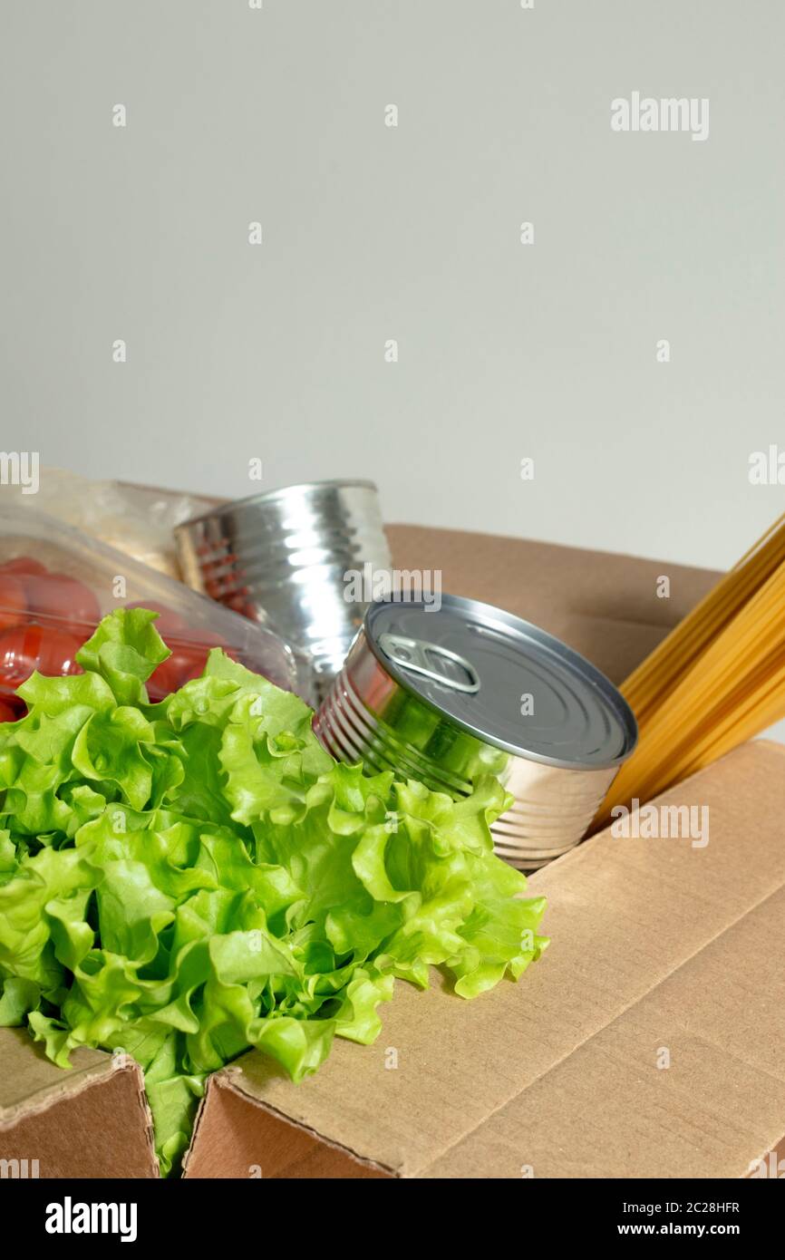 Box mit Lebensmitteln auf einem isolierten Hintergrund gefüllt. In der Box sind Gemüse, Obst, frischer Salat, Spaghetti, Konserven. Konzept der Spende, Home del Stockfoto