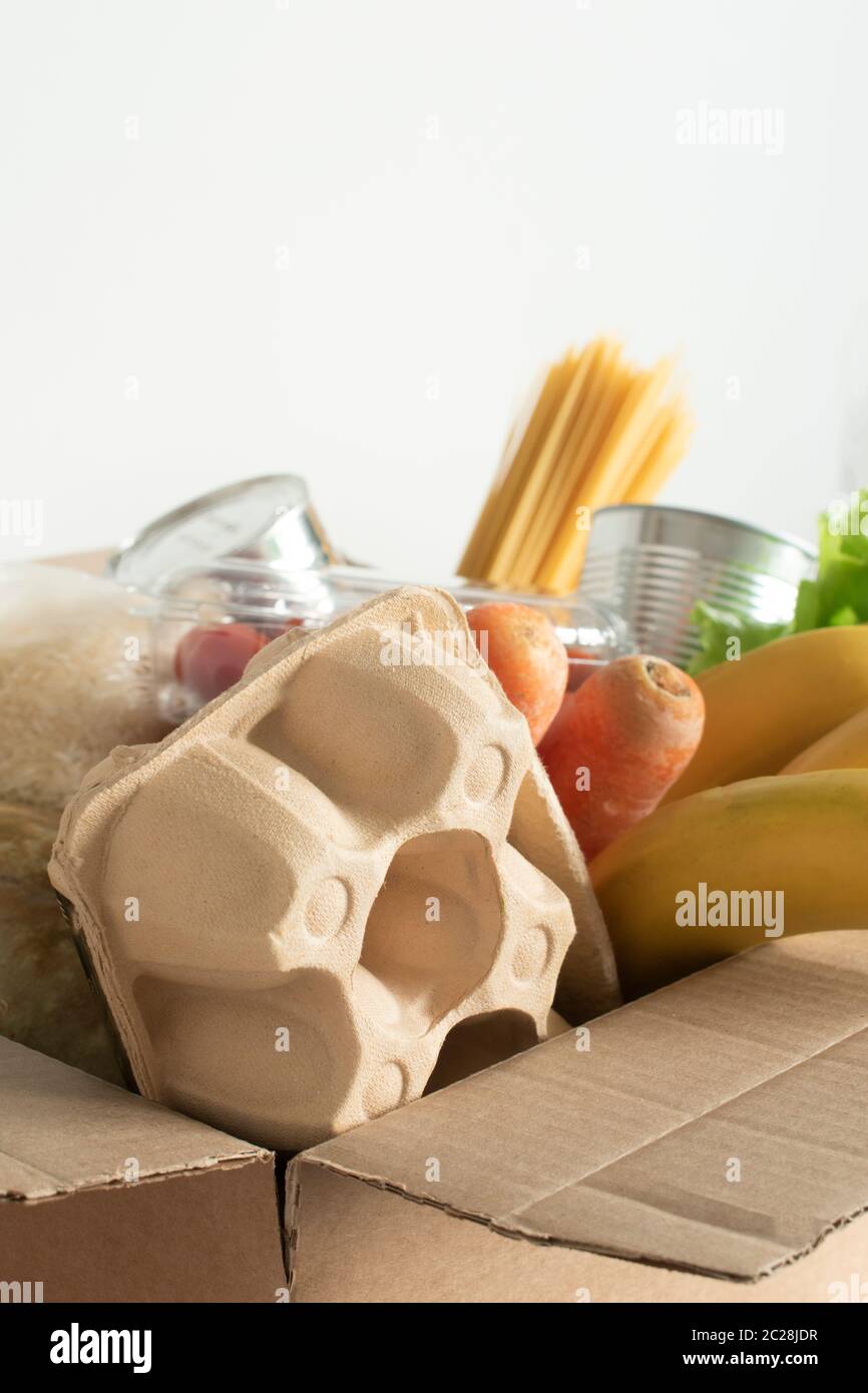 Box mit Lebensmitteln auf einem isolierten Hintergrund gefüllt. In der Box sind Gemüse, Obst, Bananen, Karotten, Eier, frischer Salat, Spaghetti, Konserven. Konz Stockfoto