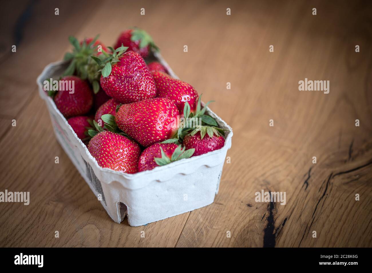 Sommerzeit: Frische rote Erdbeeren in einer Tasse, Holztisch Stockfoto