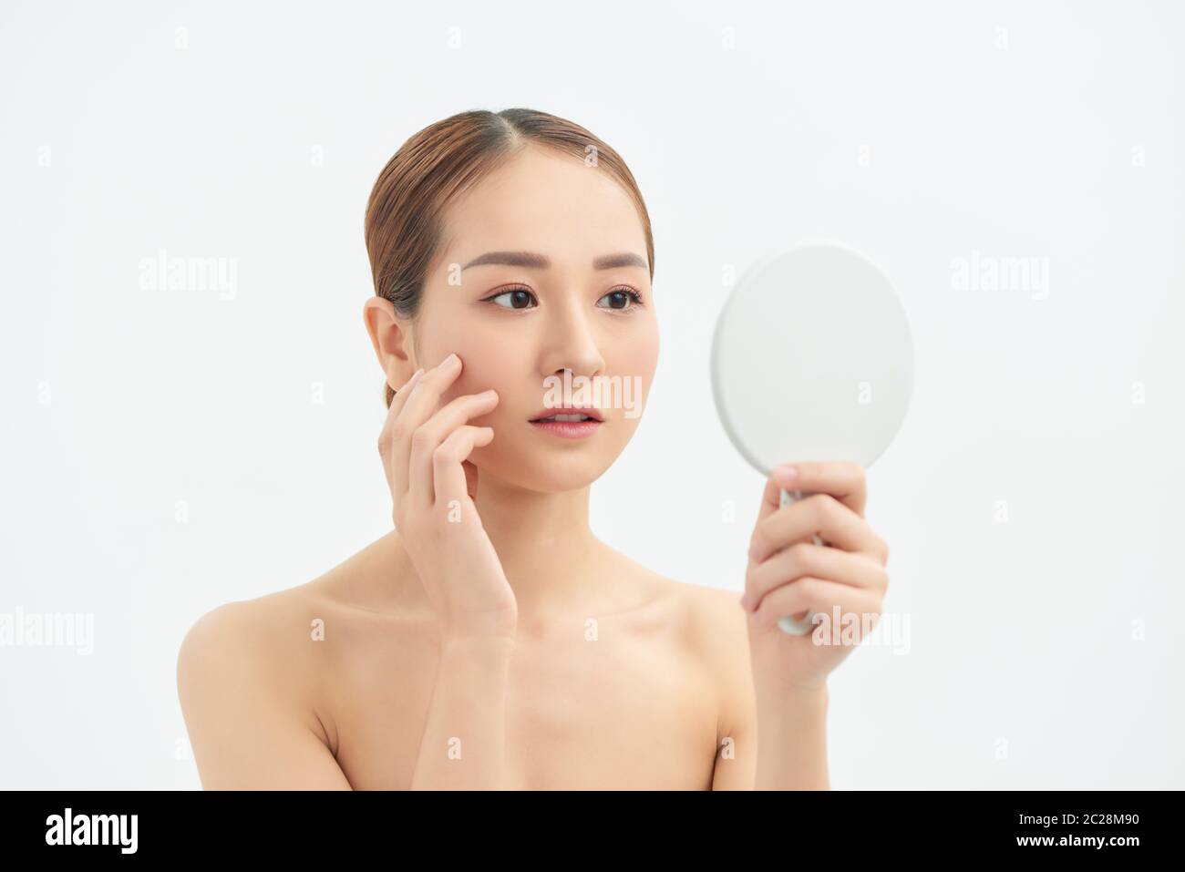 Junge asiatische Frau mit Problem Gesicht in den Spiegel mit weißem Hintergrund. Stockfoto