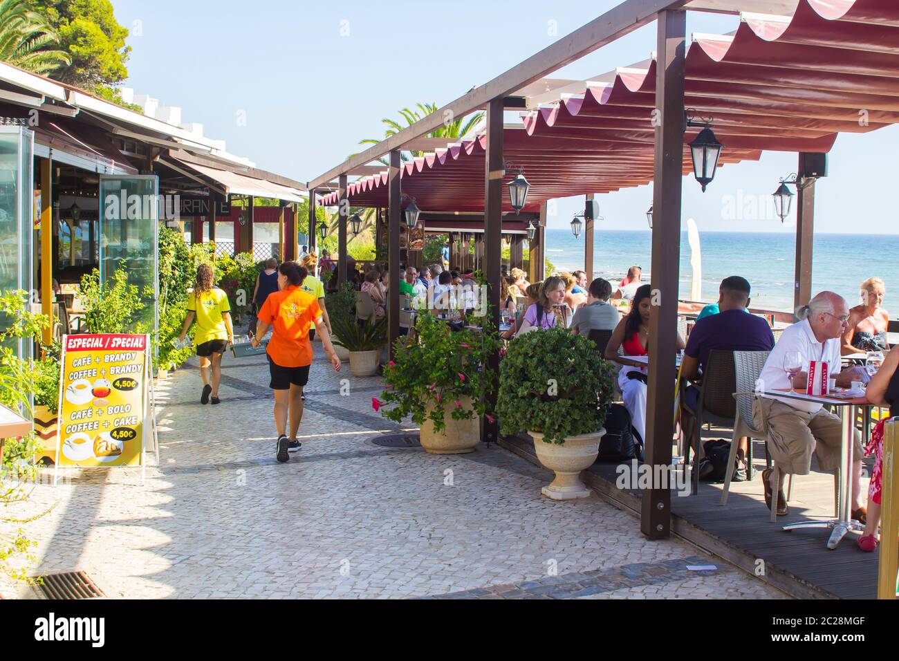 3. Oktober 2018 Patrons essen im terrassenförmig angelegten Gehweg Restaurant mit Blick auf Prai da Oura Strand in Albuferia Portugal an einem schönen heißen Nachmittag Stockfoto