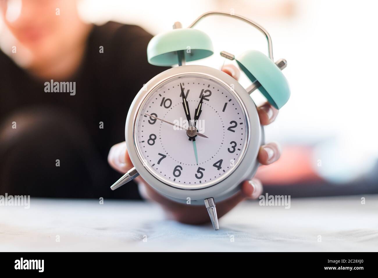 Der Mensch hält einen Wecker in der Hand, verschwommener Hintergrund Stockfoto