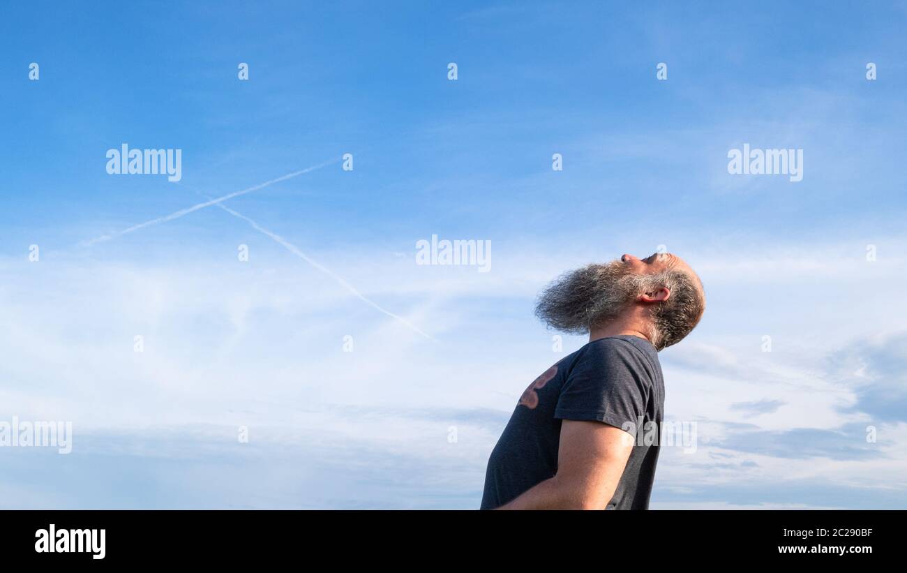 Mann, der zum blauen Himmel aufschaut Stockfoto