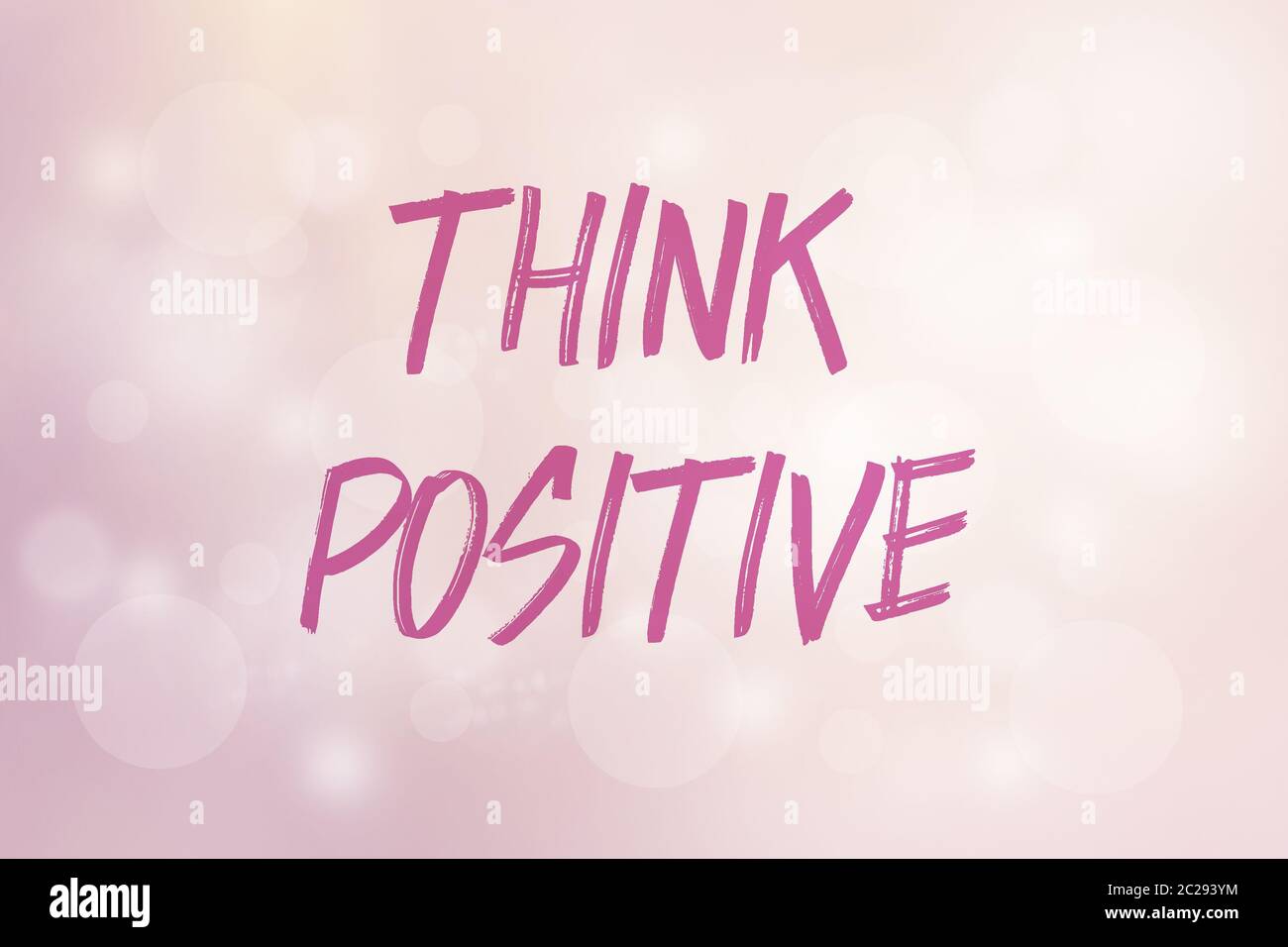 Phrase Think positive auf einem rosa Hintergrund mit glänzendem Bokeh und hellem Licht Stockfoto