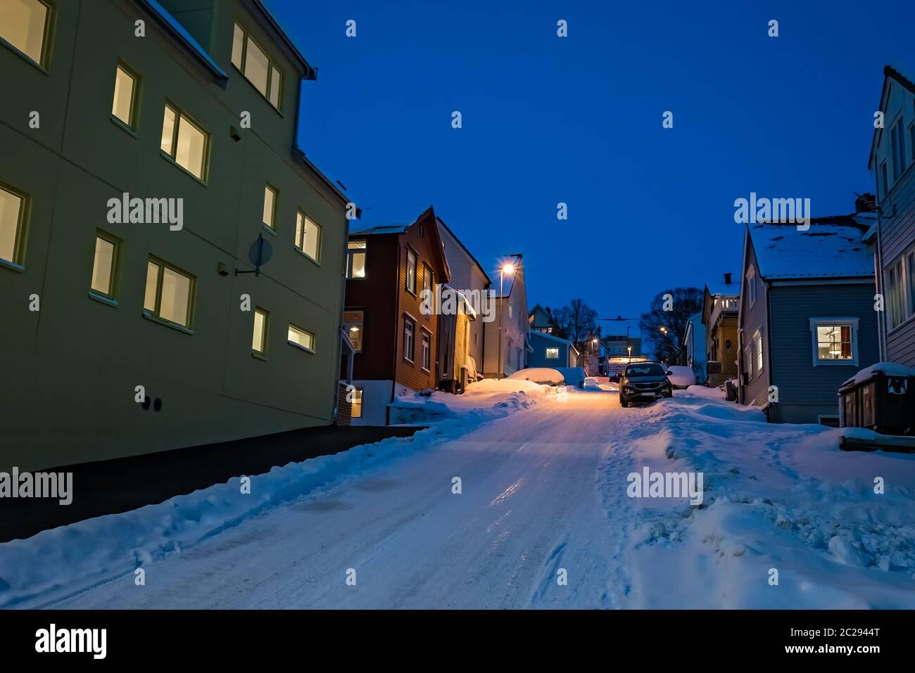 Glatt und in Schnee und Eis Wohnstraße und Hügel Häuser in Tromso bei Dämmerung abgedeckt, Norwegen Stockfoto