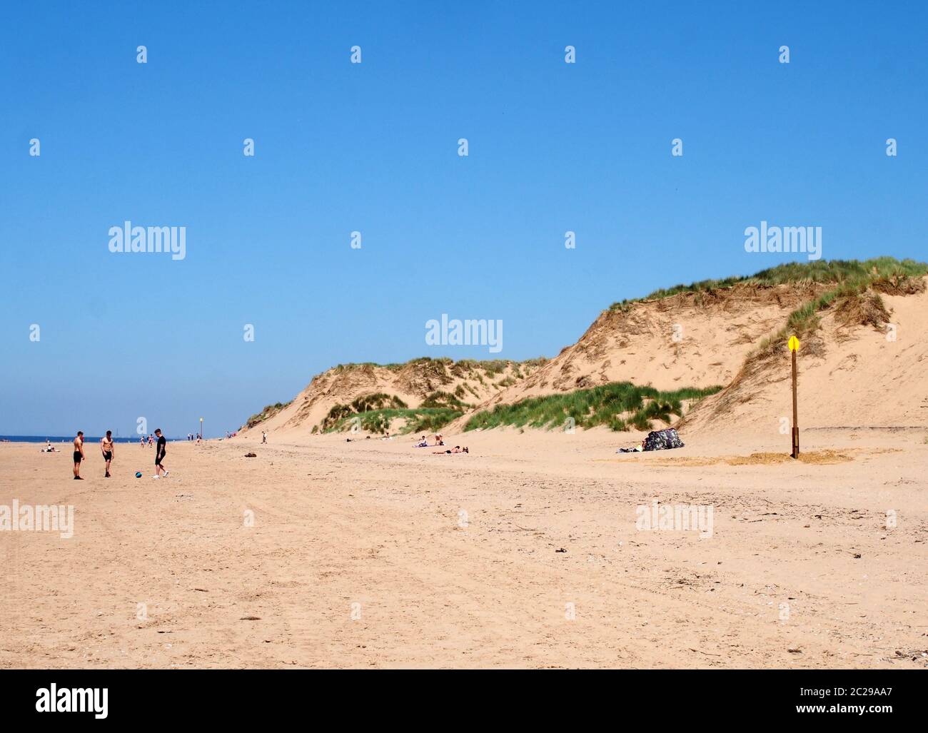 Blick auf den langen Sandstrand in formby merseyside an einem hellen Sommertag mit blauen Himmel Sanddünen und Menschen Sonnenbaden und pl Stockfoto