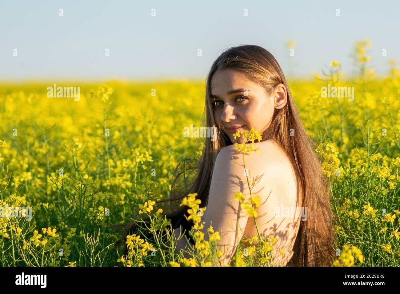 Schönes Mädchen in einem Rapsfeld, mit einer offenen Schulter. Stockfoto