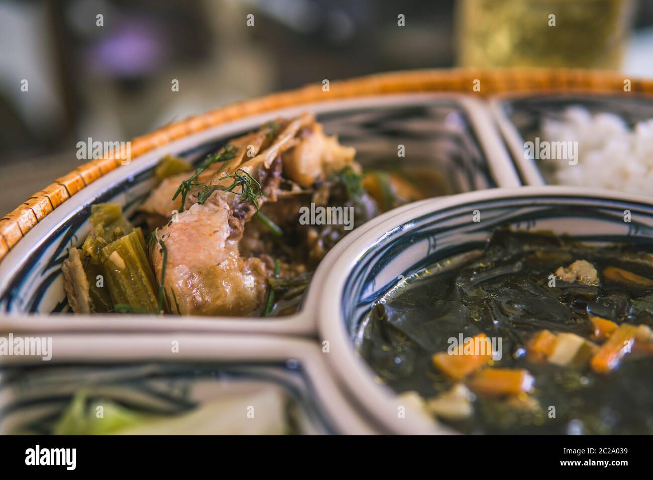 Reisschüssel mit Rattan, innen ist traditionelles vietnamesisches Mittagessen, Reis, Suppe, salziges Essen. Die Szene ist sparsam und friedlich. Essen und Trinken Konzept. Stockfoto