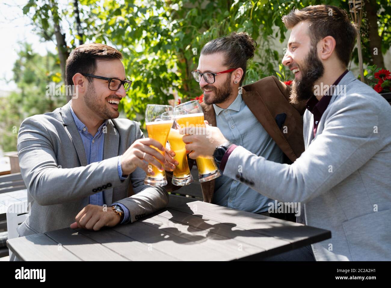 Junge Geschäftsleute trinken Bier, reden und lächeln, während sie sich in der Kneipe ausruhen Stockfoto
