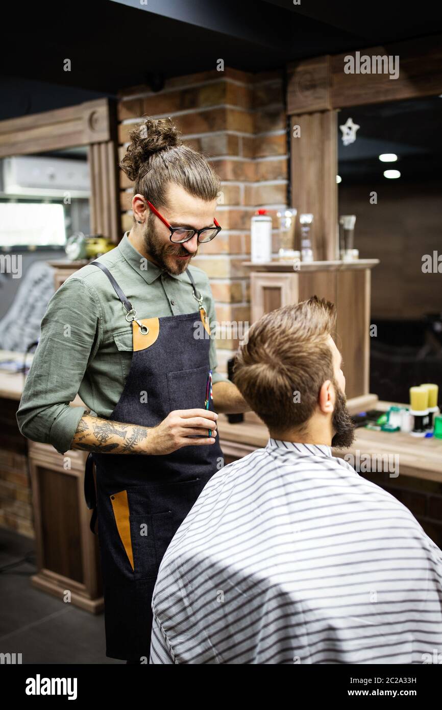 Fröhlicher junger, gutaussehender Mann, der im friseursalon einen Friseurbesuch abstattet Stockfoto